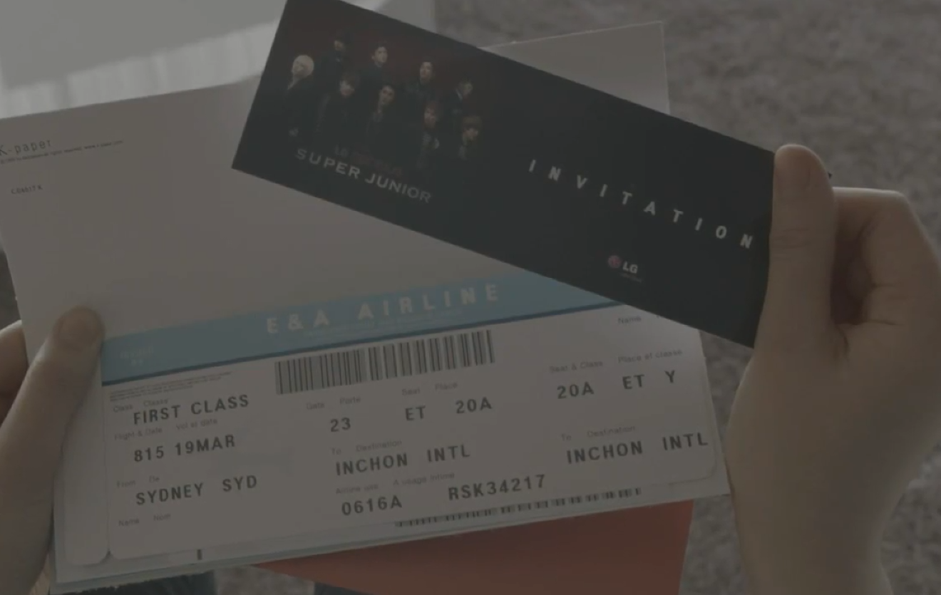 “INVITATION” 문구가 적힌 카드와 항공권을 들고 있는 모습