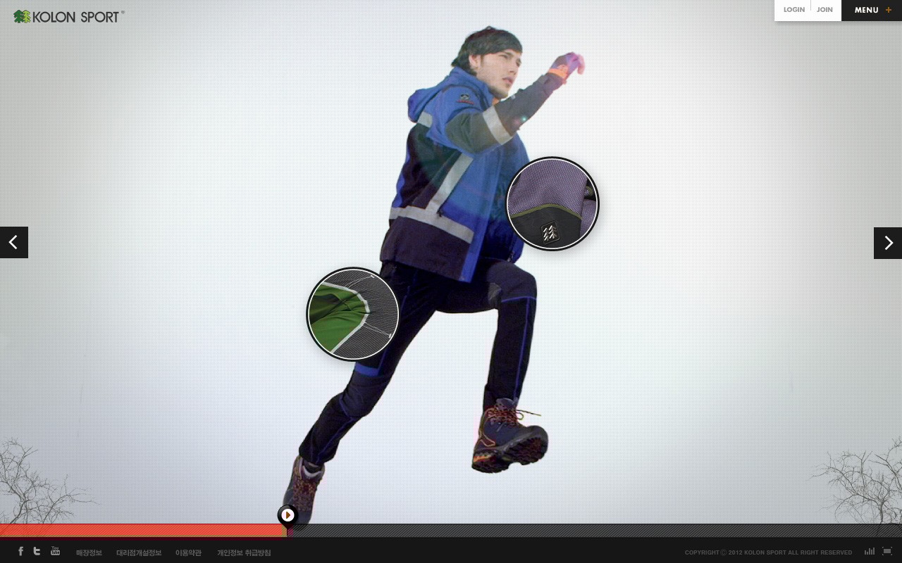 아웃도어 브랜드 코오롱스포츠 웹페이지 화면이다.  상단에는 “KOLON SPORT” 로고와 로그인, 메뉴 버튼이 보인다. 중앙에는 아웃도어 의류를 입은 남성 모델이 점프하는 동작을 하고 있으며, 의류의 소재나 디테일을 확대해 보여주는 원형 인포그래픽이 겹쳐 있다.  좌우에는 슬라이드 이동 화살표가 있고, 하단에는 재생 바 형태의 인터페이스와 SNS 아이콘, 저작권 문구가 배치되어 있다.