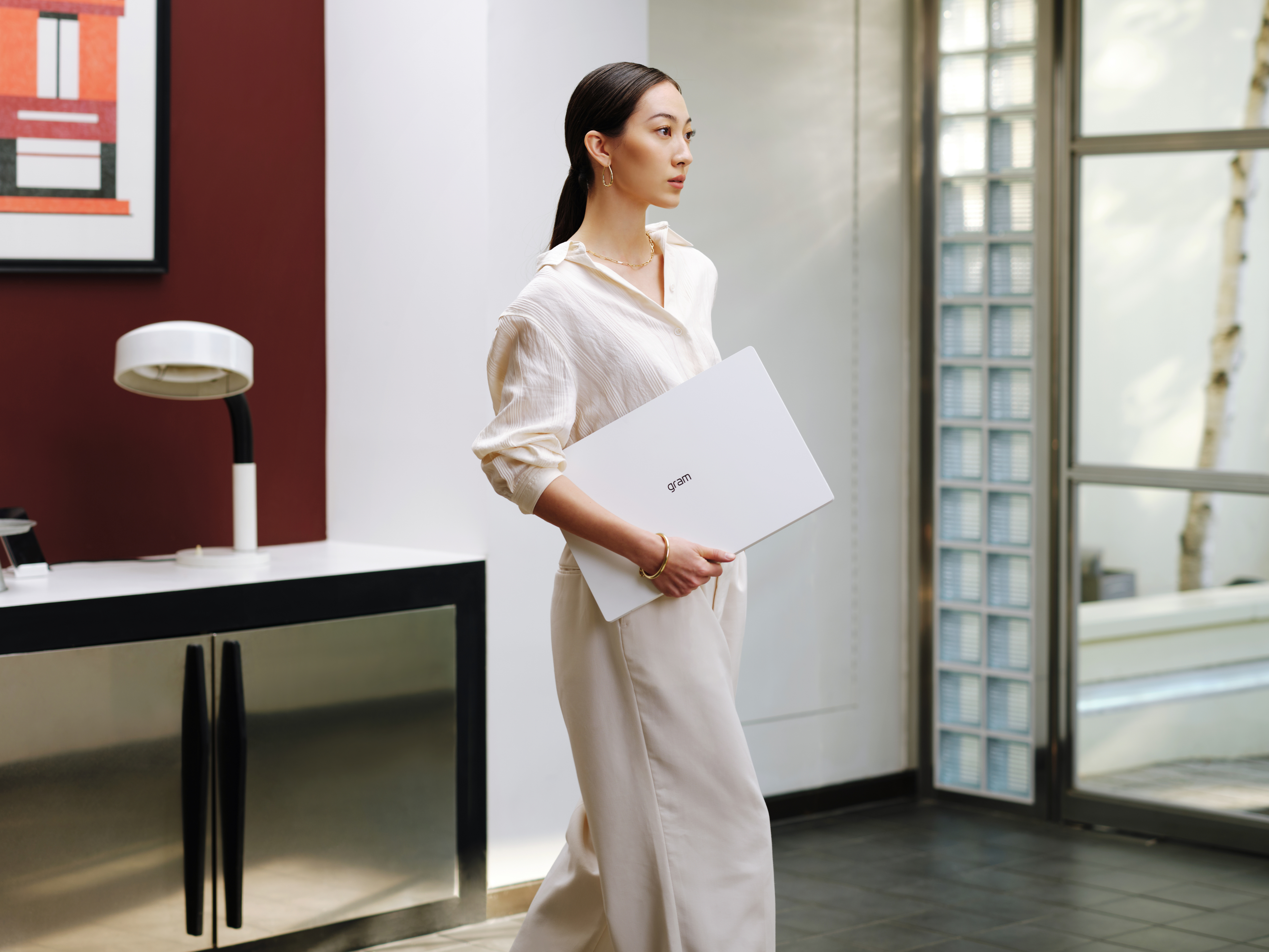 ‘gram’ 로고가 보이는 노트북을 들고 있는 인물의 상반신 모습