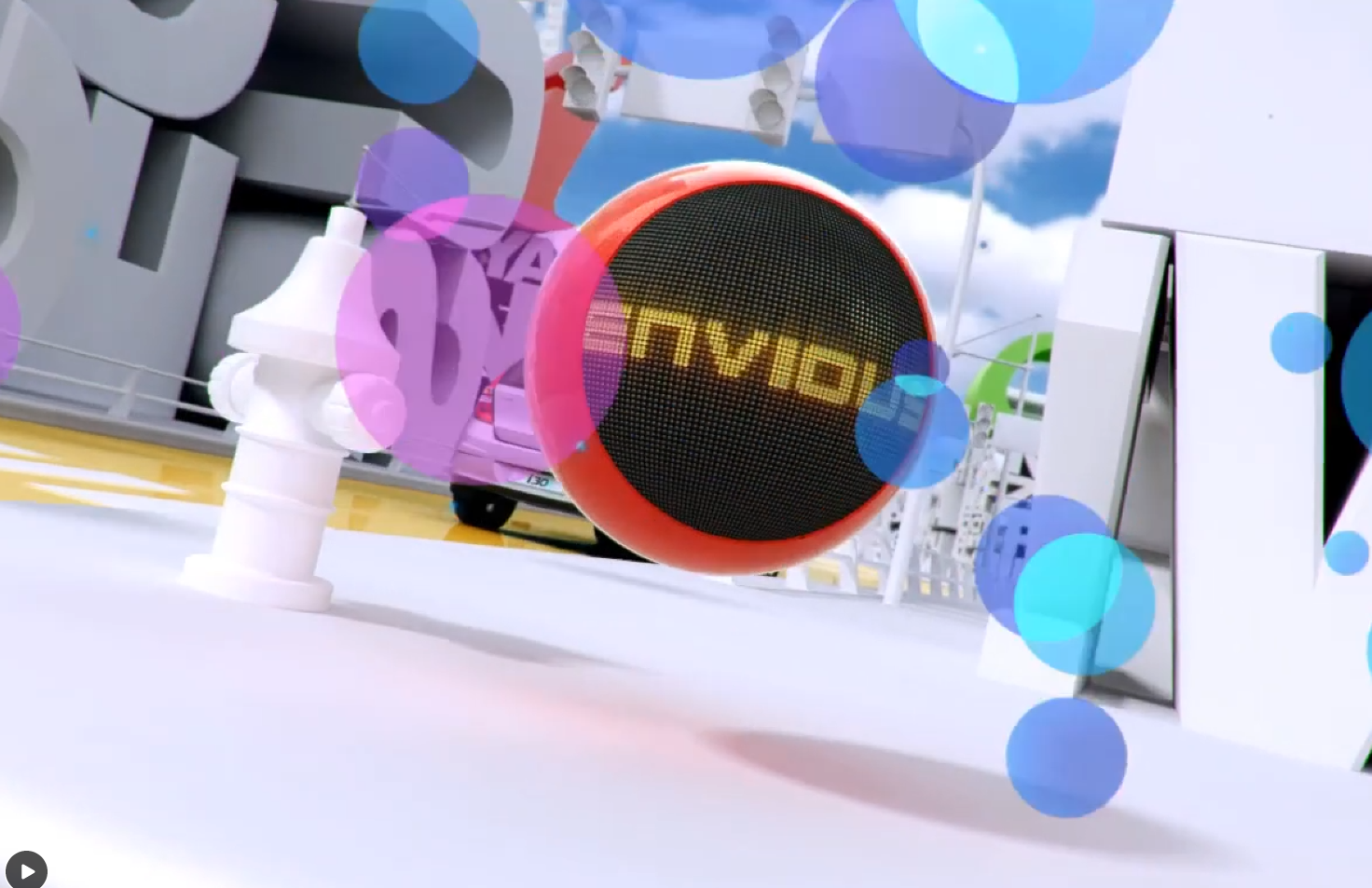 원형의 빨간 스피커가 화면 중앙에 크게 보인다. 전면에는 검은 메쉬 그릴이 있고, 그 위에 노란색 글자가 표시되어 있다. 주변에는 보라색과 파란색의 반투명 원형 그래픽이 겹쳐 있으며, 뒤쪽에는 i30 자동차와 전시장처럼 보이는 배경이 흐릿하게 보인다.